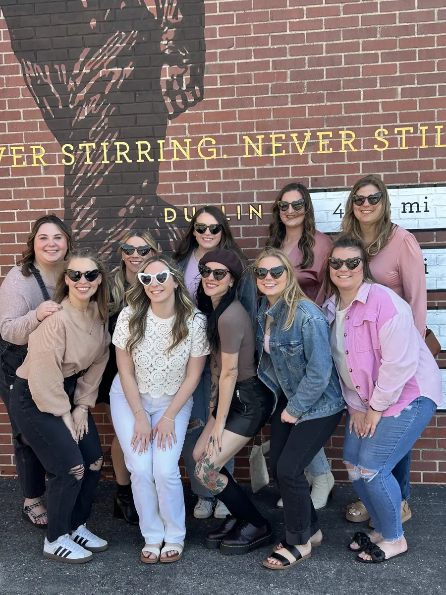 Bachelorette group posing at a brick mural