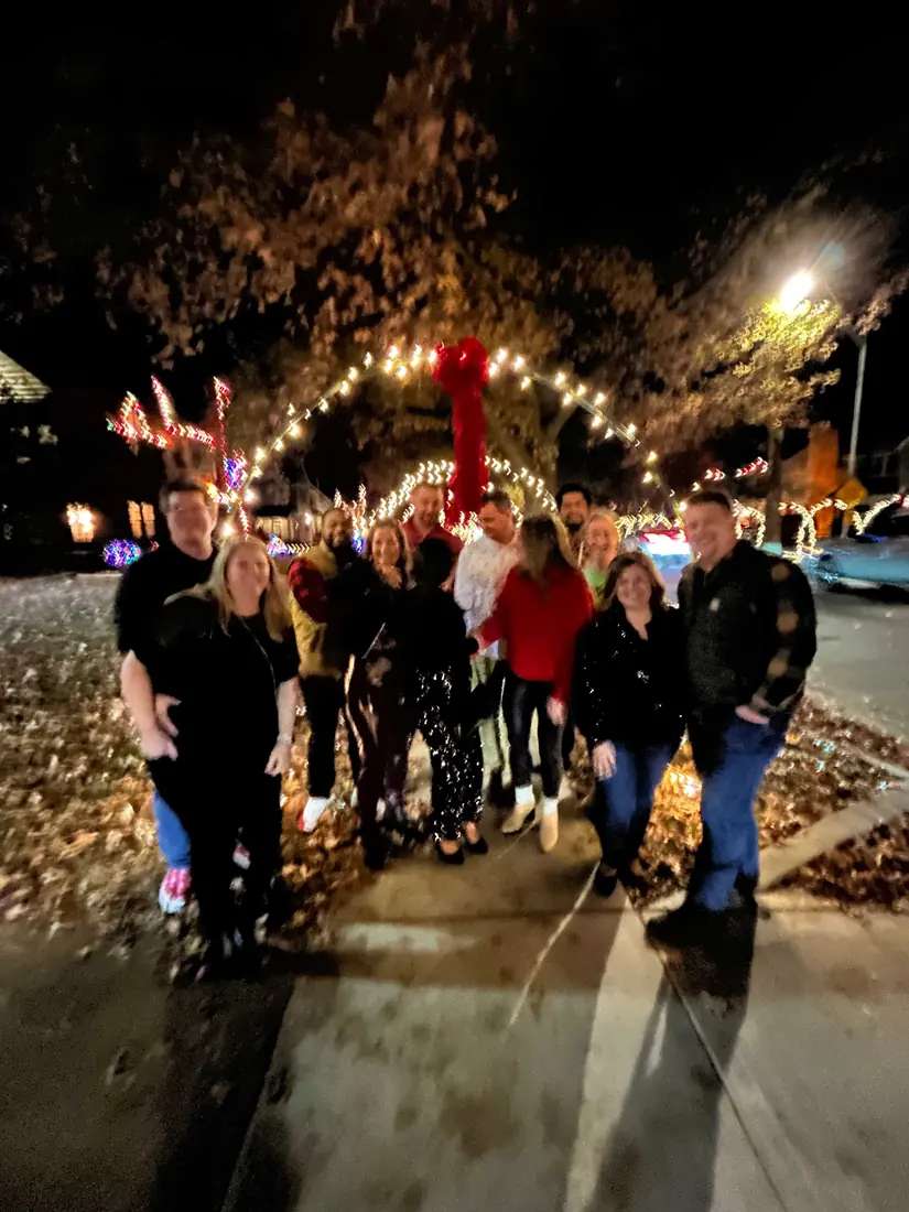 A group under a lighted arch with a red bow